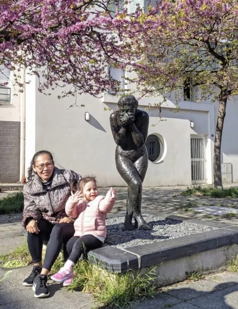 Une aide à domicile promenant un enfant sous les cerisiers en fleurs